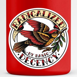 Może przedstawiać: Czerwony kubek z okrągłym wzorem w stylu tatuażu. Projekt zawiera ptaka z czerwonymi i brązowymi skrzydłami, trzymającego zieloną gałązkę oraz napis "RADICALIZED BY BASIC DECENCY" w banerze.
