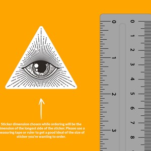 Op de afbeelding: Zwart-witte illustratie van een alziend oog in een driehoek met lichtstralen die uit het oog komen. Naast de afbeelding is een liniaal afgebeeld om de grootte van de sticker aan te geven.