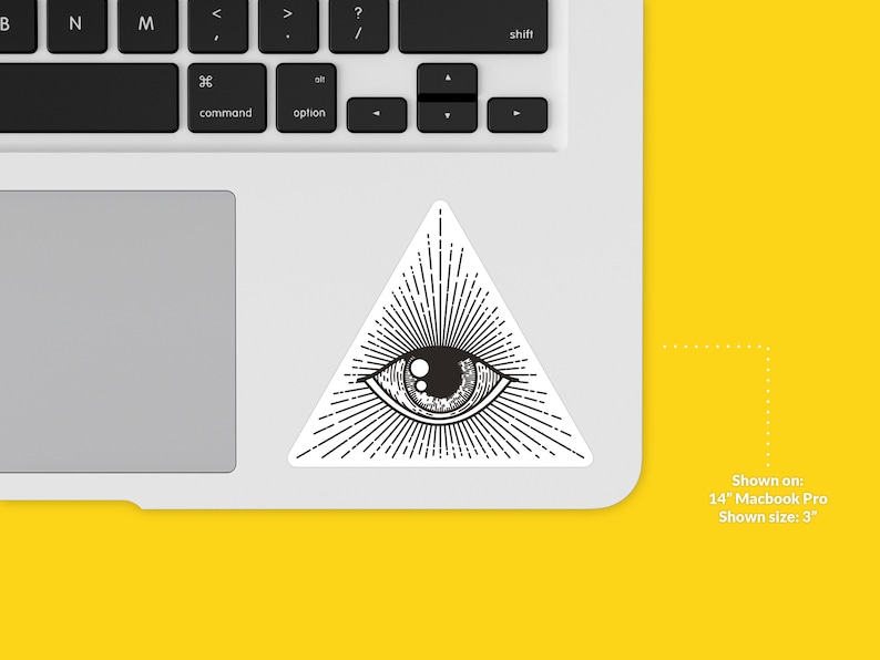 Op de afbeelding: Een zwart-witte sticker van een oog in een driehoek met stralen licht die eruit komen. De sticker is te zien op een 14-inch Macbook Pro-laptop. De sticker is 7,6 cm groot.