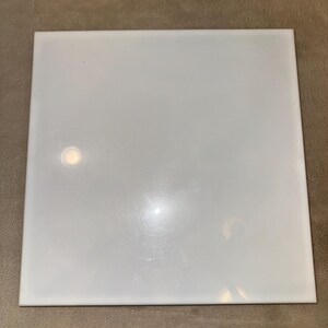 May include: A white ceramic tile with a smooth, glossy finish.