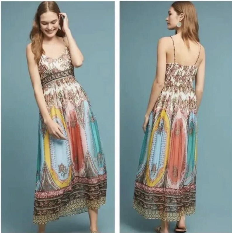 May include: A long, patterned dress with spaghetti straps. The dress features a mix of colors including blue, yellow, orange, and pink. The bodice has a floral pattern, and the skirt has a paisley design. The dress is floor-length.