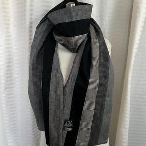 Może przedstawiać: Szalik w czarno-szary kratę z czarnym paskiem w środku. Szalik ma metkę z napisem "J.C. Penney".