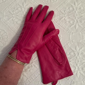 May include: A pair of pink leather gloves. The gloves are made of a soft, supple leather and have a classic design.