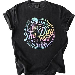 May include: Black t-shirt with a rainbow-colored graphic of a skeleton with the text "Have the Day You Deserve."