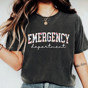 May include: A dark gray t-shirt with a floral print design that says "EMERGENCY department" in white letters.