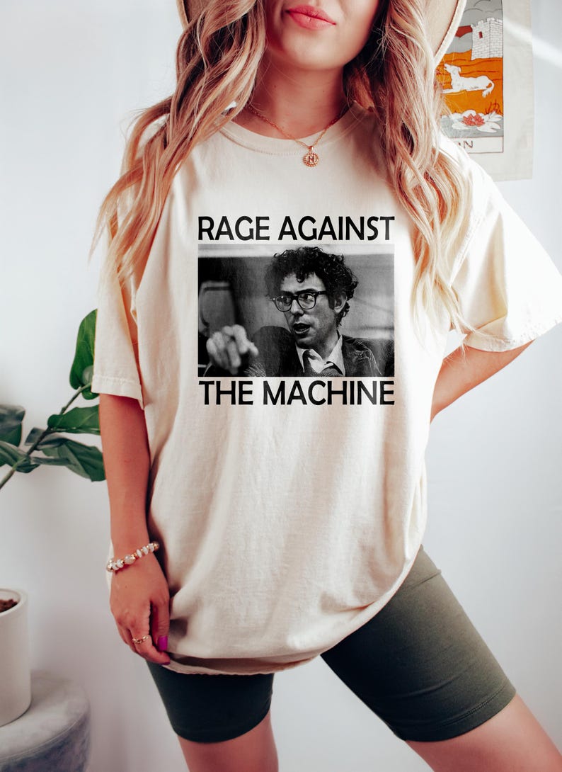 May include: A white t-shirt with a black and white image of a man wearing glasses and the text "Rage Against The Machine".