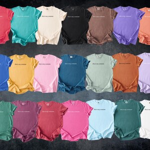 May include: A collection of twenty-one colorful t-shirts in various shades, including red, teal, cream, black, brown, purple, and orange. Each shirt has the phrase "this is my costume" printed in white across the chest. The shirts are arranged in rows.