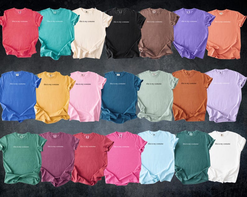 May include: A collection of twenty-one colorful t-shirts in various shades, including red, teal, cream, black, brown, purple, and orange. Each shirt has the phrase "this is my costume" printed in white across the chest. The shirts are arranged in rows.