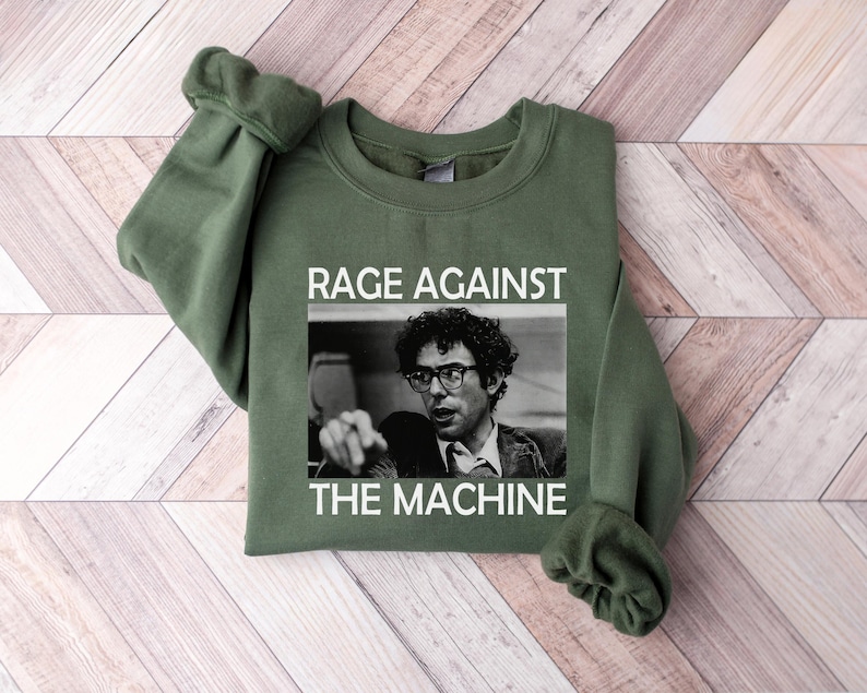 May include: A green sweatshirt with the text "Rage Against The Machine" and a black and white image of a man with glasses.