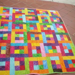 May include: A colorful patchwork quilt with a variety of squares and rectangles in shades of pink, purple, blue, green, yellow, orange, and red.