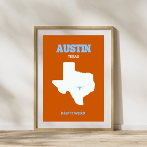 Puede incluir: Una impresión enmarcada con un fondo naranja que presenta el texto "AUSTIN TEXAS" en letras azules. Un contorno blanco del estado de Texas con un longhorn azul en su interior está centrado en la impresión. El texto "KEEP IT WEIRD" está en la parte inferior de la impresión.