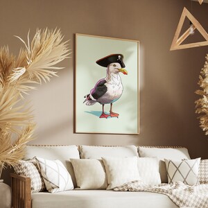 May include: A framed illustration of a seagull wearing a pirate hat with a skull and crossbones design. The seagull is standing on a light blue background.