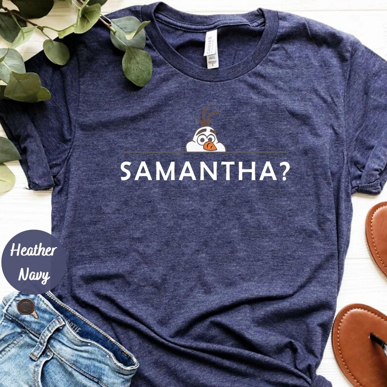 K&ouml;nnte beinhalten: Ein marineblaues T-Shirt mit einer wei&szlig;en Grafik von Olaf aus Frozen, der &uuml;ber eine Linie schaut, unter der der Text "SAMANTHA?" gedruckt ist.