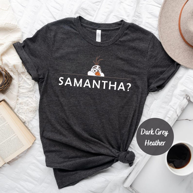 K&ouml;nnte beinhalten: Dunkelgraues T-Shirt mit Melange-Effekt und einem wei&szlig;en Aufdruck von Olaf aus Frozen, der &uuml;ber einer Linie lugt, unter der der Text "SAMANTHA?" steht.