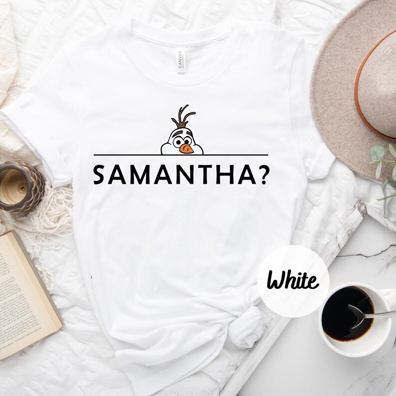 K&ouml;nnte beinhalten: Wei&szlig;es T-Shirt mit einem Cartoon-Bild von Olaf aus Frozen, der &uuml;ber eine Linie schaut, unter der der Text "SAMANTHA?" gedruckt ist.