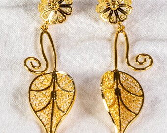 May include: A pair of gold filigree earrings with a leaf design. The earrings are delicate and intricate, with a floral detail at the top.