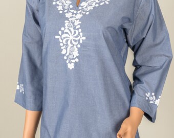 May include: A light blue denim top with white embroidered floral designs around the neckline and on the sleeves.