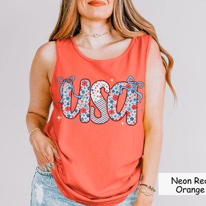 Neon red-orange Comfort Colors tank top with floral USA graphic. A trendy patriotic tank for women, ideal for Independence Day, backyard BBQs, and summer events. This 4th of July shirt makes the perfect red white and blue outfit idea
