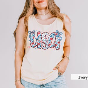 Ivory USA tank top for women with floral patriotic graphic. This neutral-toned 4th of July shirt is perfect for summer picnics, Independence Day outfits, and casual red white and blue looks in soft Comfort Colors fabric.