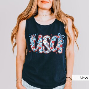 Navy Comfort Colors tank with floral USA design in red, white, and blue. A classic patriotic tank for women perfect for 4th of July parades, summer lake days, or America-themed outfits. Styled with casual denim.