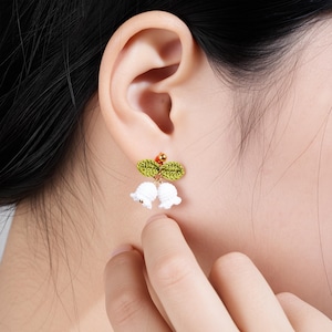 May include: A white ceramic mug with a black handle and the text "But First, Coffee" in a bold, black font. The mug is set against a blurred background, suggesting a cozy setting.