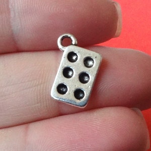 May include: Silver charm shaped like a muffin tin with six round cavities.