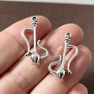 May include: Two silver charm pendants shaped like a hookah or water pipe. The charms have a detailed design and are perfect for adding a unique touch to jewelry.