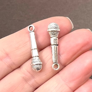 May include: Two silver-toned microphone charms with a loop at the top for attaching to jewelry or crafts.