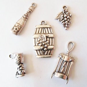 May include: Five silver charm pendants with a wine theme. The charms include a wine bottle, a wine barrel, a bunch of grapes, a wine glass, and a corkscrew.