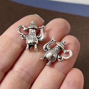 May include: Two silver teapot charms with intricate details. One charm has the words "Tea Time" engraved on it.