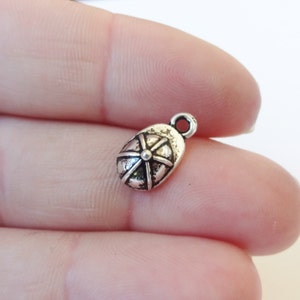 May include: Silver charm in the shape of a baseball cap. The charm has a detailed design and a loop for attaching to a bracelet or necklace.