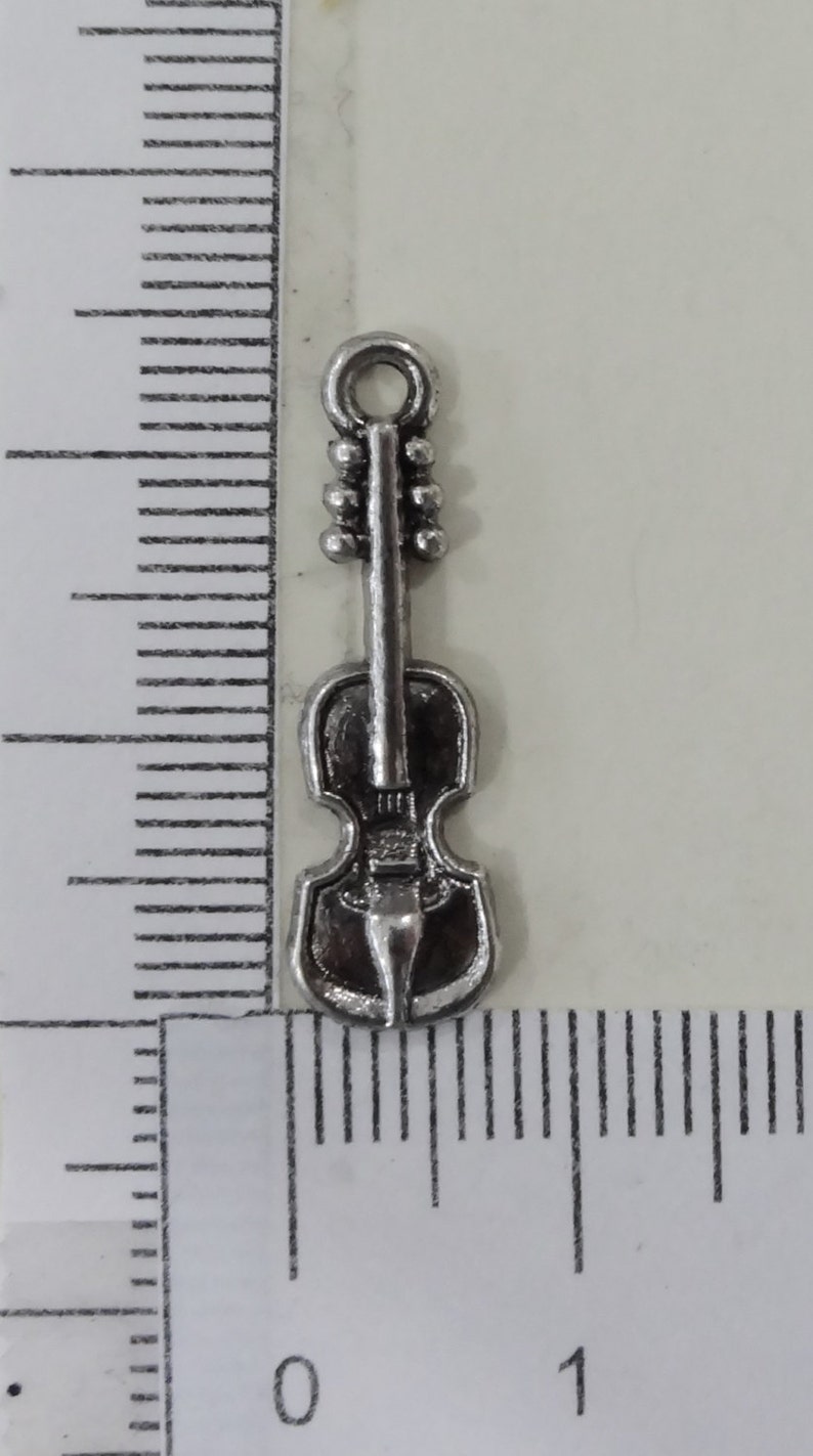 May include: Silver-toned metal charm shaped like a violin. The charm has a loop at the top for attaching to a necklace or bracelet.