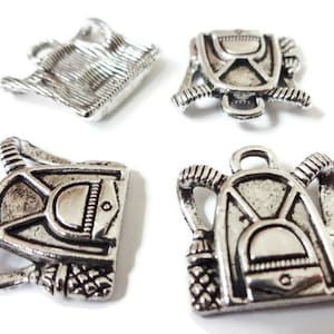 May include: Four silver charm pendants in the shape of backpacks. The charms have a detailed design and are perfect for adding a touch of whimsy to jewelry.