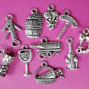 May include: A set of ten silver-toned metal charms with wine-themed designs. The charms include a wine bottle, a wine glass, a corkscrew, a wine barrel, a bunch of grapes, a wine basket, a wine bottle with two glasses, and a charm that says "Cheers".