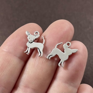 May include: Two silver charm pendants in the shape of a chihuahua dog. The charms are detailed and have a shiny finish.