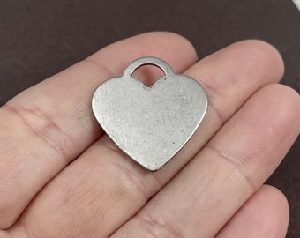 May include: Silver heart-shaped charm with a loop at the top. The charm is smooth and has a slightly aged finish.