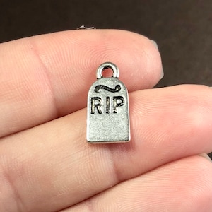 May include: Silver charm shaped like a tombstone with the inscription "RIP" on it.
