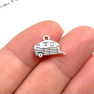 May include: Silver charm in the shape of a vintage camper trailer. The charm has a detailed design with windows and a door.