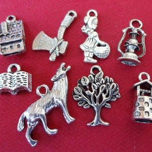 May include: A collection of silver-toned charms featuring storybook themes. Includes a house, axe, girl with basket, lantern, open book, howling wolf, tree, and well. These charms are ideal for jewelry making or crafting projects.