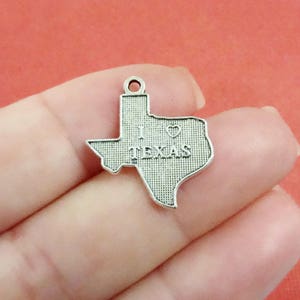 May include: Silver charm in the shape of the state of Texas with the words "I love Texas" and a heart.