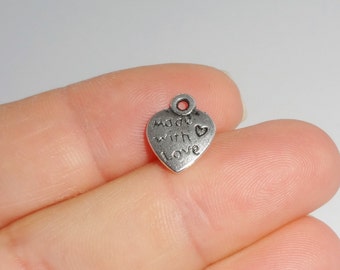 May include: Silver heart-shaped charm with the text "Made with Love" and a small heart symbol.