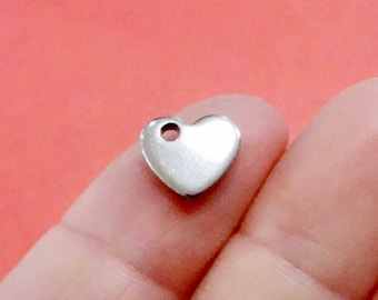 May include: A silver heart-shaped charm with a small hole in the center. The charm is about 1 inch in size.