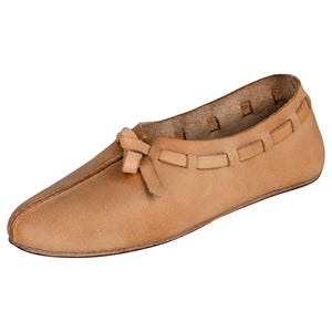 Könnte beinhalten: Ein einzelner, hellbrauner Lederschuh mit spitzer Zehenpartie und einer kleinen Schleife oben. Der Schuh hat ein einfaches Slip-on-Design mit dekorativen Aussparungen am oberen Rand. Der Schuh scheint handgefertigt zu sein.
