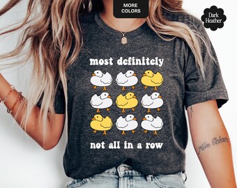May include: Dark heather gray t-shirt featuring a grid of cartoon ducks, some yellow and some white, with the text "most definitely not all in a row". The shirt has a crew neck and short sleeves.