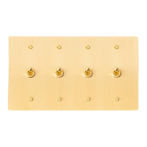 May include: A brass light switch plate with four toggle switches. The plate is a rectangular shape and has a brushed finish.