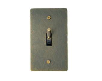 May include: A brass light switch with a textured finish and a black toggle. The switch has two brass screws.