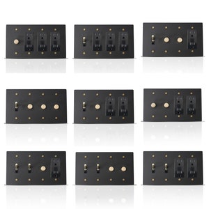 May include: Nine black electrical switch plates with brass-colored toggle switches, outlets, and round dimmer switches. Each plate has a rectangular shape and is mounted with small brass-colored screws. The plates are arranged in a grid pattern.