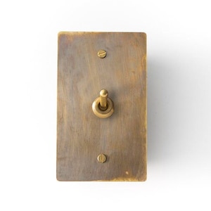 Puede incluir: Un interruptor de luz de latón con un interruptor de palanca y dos tornillos. El interruptor tiene un acabado desgastado.