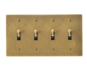 May include: A brushed brass wall plate with four toggle switches. Each switch has a black toggle and a brass knob.