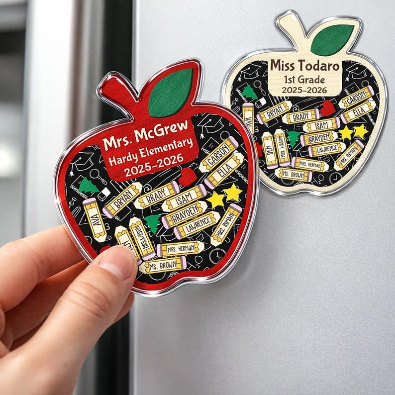 May include: Two apple-shaped magnets with clear borders. One is red with a green leaf, the other is light wood-toned with a green leaf. Both have student names on pencils. The red magnet says "Mrs. McGrew, Hardy Elementary 2025-2026". The other says "Miss Todaro, 1st Grade 2025-2026".